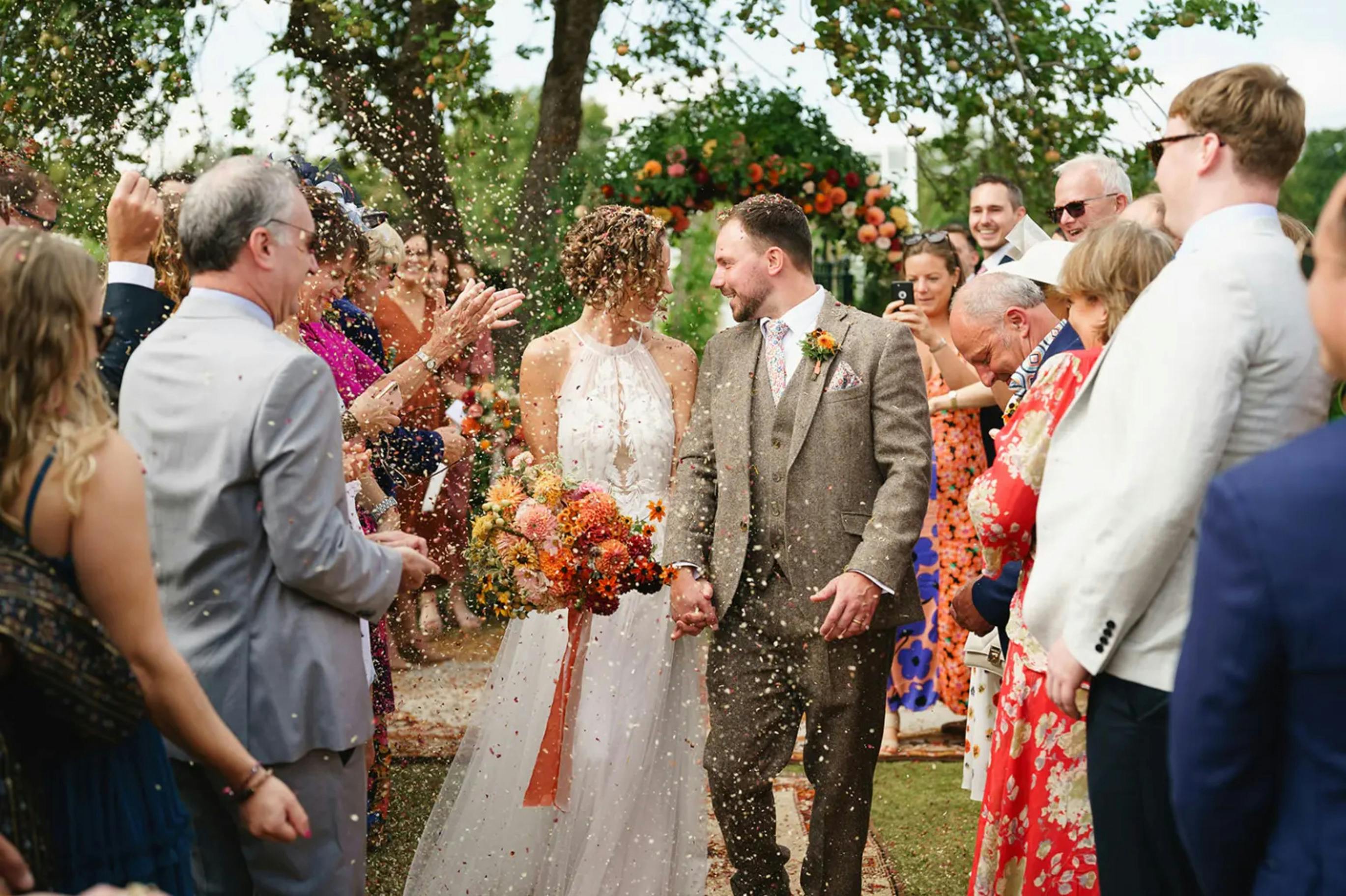Wedding guests throwing confetti as bride and groom walk through